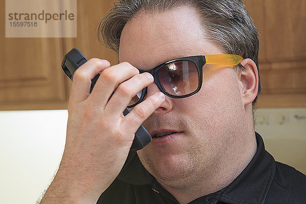 Ein Mann mit angeborener Blindheit nutzt eine Hörhilfe  um seine Textnachrichten zu hören