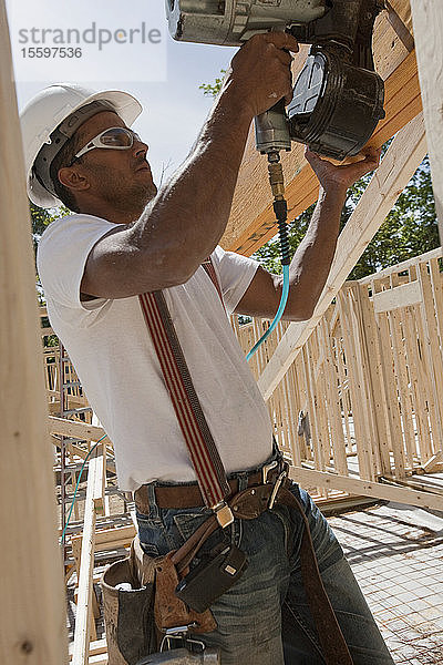 Zimmermann mit einer Nagelpistole auf einer Baustelle
