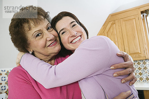 Porträt einer lächelnden Großmutter  die ihre Enkelin umarmt.