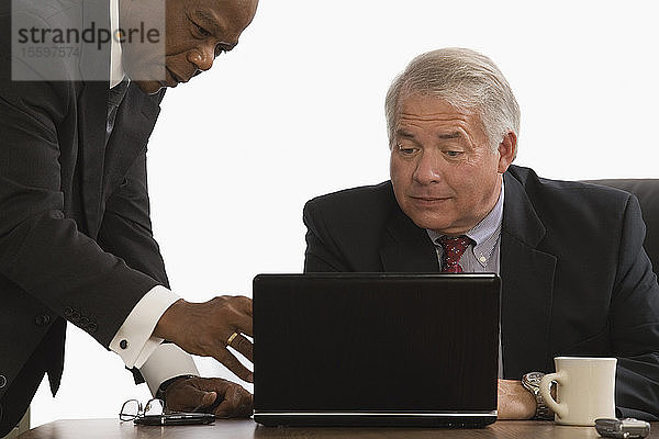 Zwei Geschäftsleute schauen auf einen Laptop in einem Büro