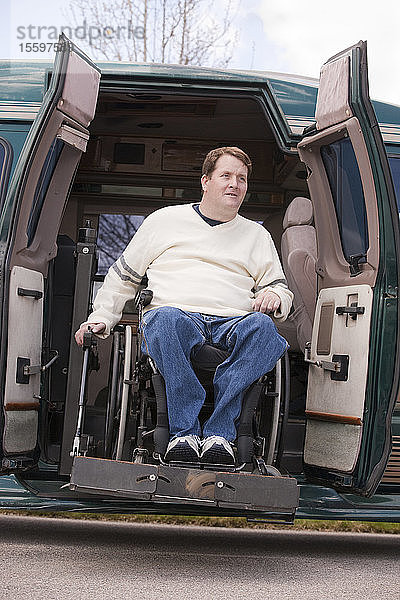 Mann mit Rückenmarksverletzung im Rollstuhl  der aus einem rollstuhlgerechten Lieferwagen aussteigt