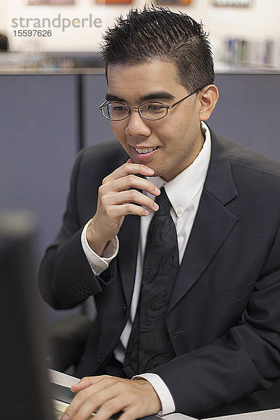 Asiatischer Mann mit Autismus arbeitet am Computer in einem Büro
