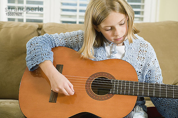 Blick auf ein süßes Mädchen  das Gitarre spielt.