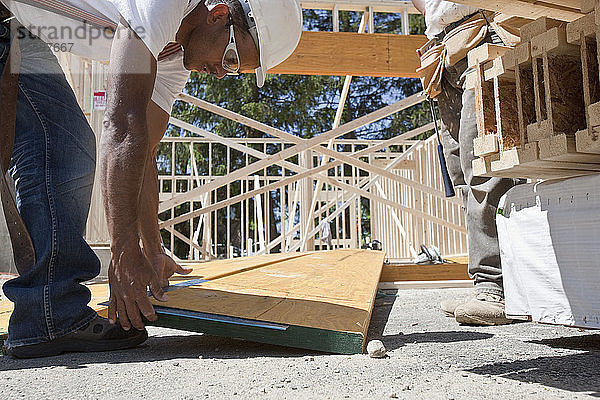 Zimmerleute arbeiten auf einer Baustelle an einem Lamellenbalken