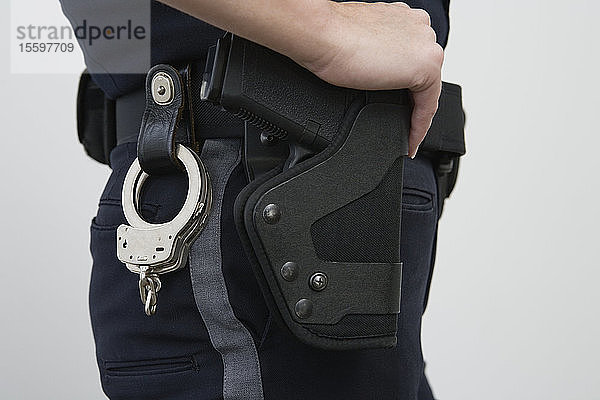 Eine Polizistin mit einer Pistole im Halfter und Handschellen.