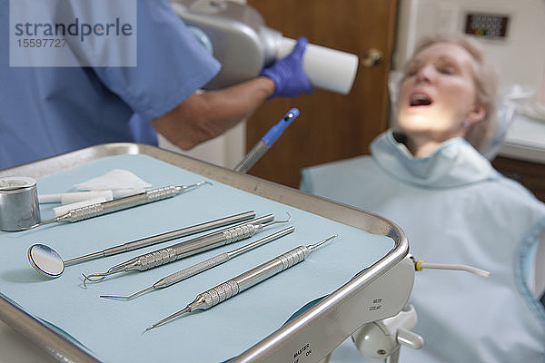 Zahnärztliche Ausrüstung mit einer Zahnärztin  die einen Patienten untersucht
