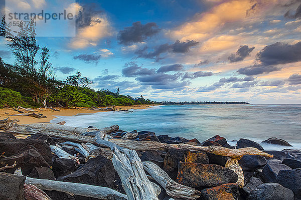 Sonnenaufgang über dem Strand von Lydgate und dem Meer mit Felsen und Treibholz im Vordergrund und der Küstenlinie in der Ferne; Kapaa  Kauai  Hawaii  Vereinigte Staaten von Amerika