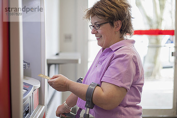 Frau mit zerebraler Lähmung an einem Geldautomaten