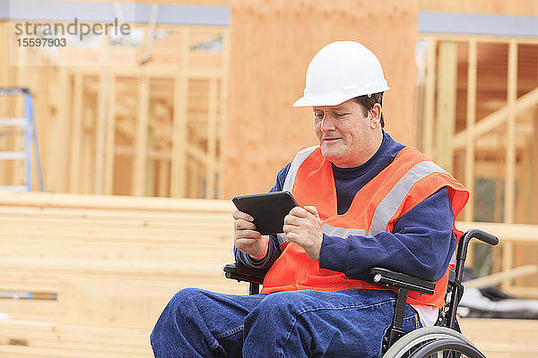 Bauingenieur mit Querschnittslähmung nutzt Tablet  um sich auf der Baustelle Notizen zu machen