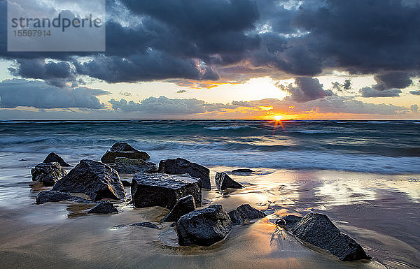 Sonnenaufgang über dem Pazifischen Ozean von den Felsen am Ufer des Lydgate Beach und dunklen Wolken am Himmel; Kapaa  Kauai  Hawaii  Vereinigte Staaten von Amerika