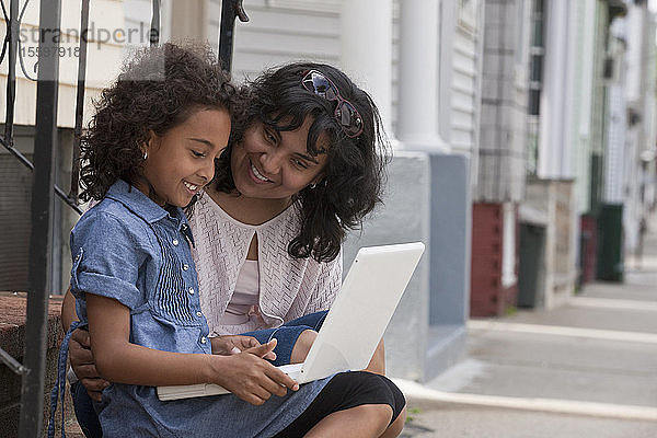 Hispanisches Mädchen benutzt mit ihrer Mutter einen Laptop