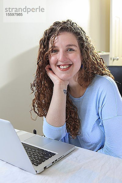Frau mit Muskeldystrophie arbeitet an ihrem Laptop in ihrem Büro