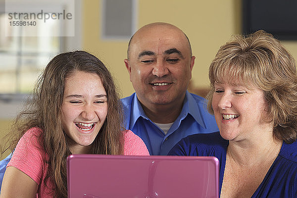 Tochter mit Vater und Mutter lachend am Laptop