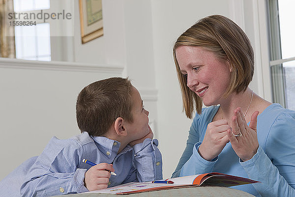 Frau gebärdet das Wort Draw in amerikanischer Zeichensprache  während sie ihren Sohn unterrichtet