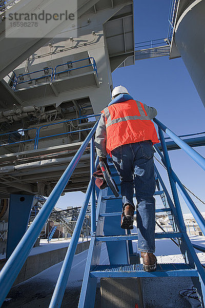 Ingenieur klettert auf den Turm einer Materialfabrik
