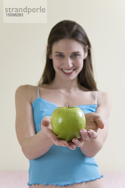 Eine schöne junge Frau hält einen grünen Apfel.