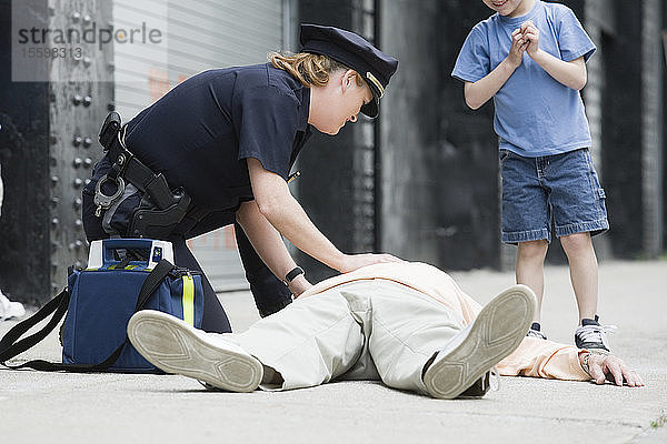Polizeibeamtin leistet einem älteren Mann erste Hilfe