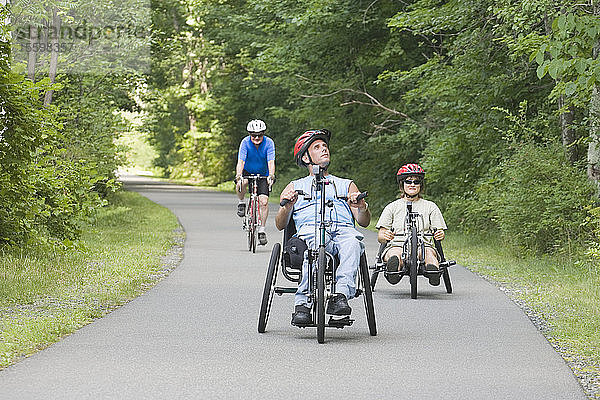Drei Freunde fahren adaptive Fahrräder  einer mit einer Rückenmarksverletzung