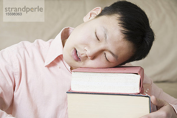 Nahaufnahme eines schlafenden Teenagers auf einem Bücherstapel