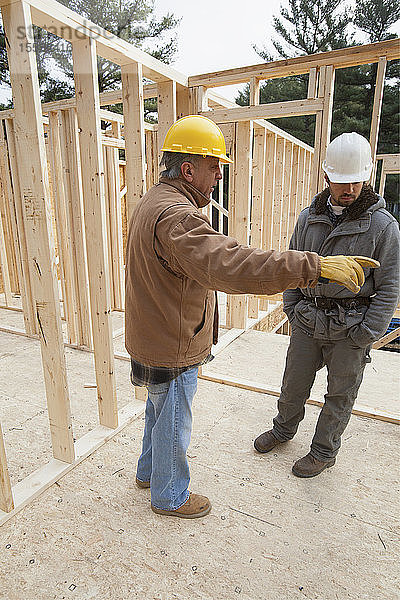 Ein Bauleiter bespricht den Bau eines Hauses mit einem Zimmerer