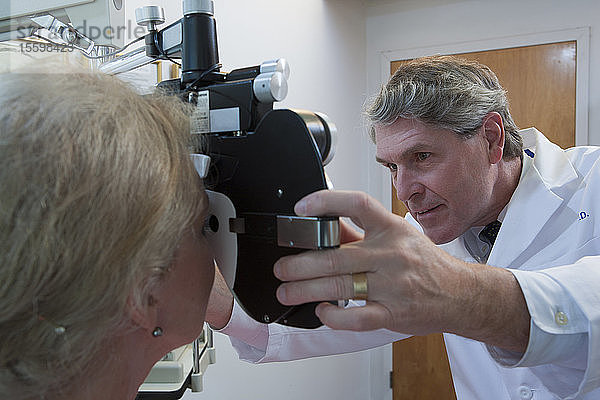 Augenarzt bei der Untersuchung der Augen einer Frau mit einem Phoropter