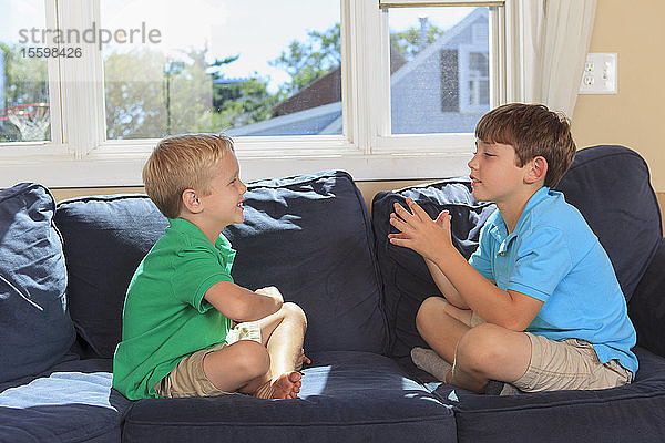 Hörgeschädigte Jungen spielen und gebärden in amerikanischer Zeichensprache auf ihrer Couch