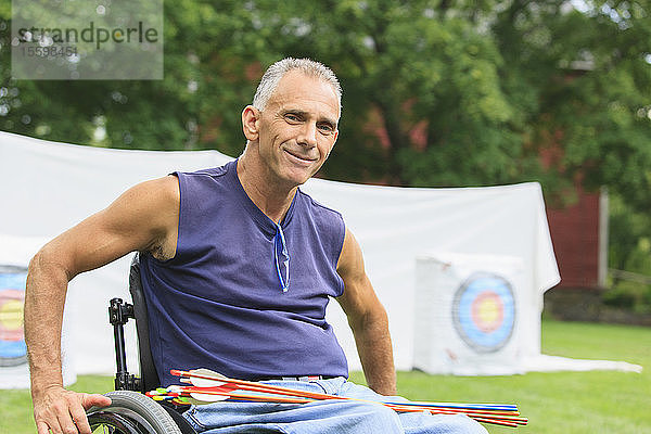 Mann mit Querschnittslähmung im Rollstuhl bereitet sich auf Bogenschießen vor