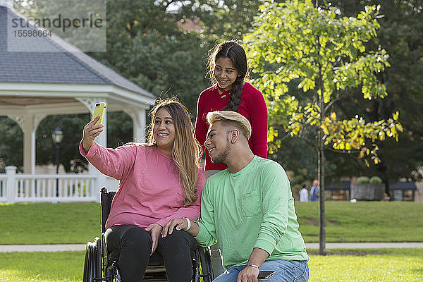 Drei Freunde machen ein Selfie  einer mit einer Rückenmarksverletzung