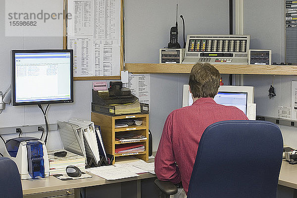 Rückansicht eines Mannes bei der Arbeit in einem Kontrollraum