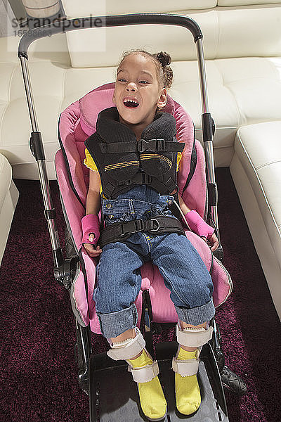 Kleines Mädchen mit Cerebralparese bereit für eine Fahrt im Kinderwagen