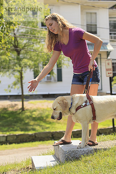 Studentin mit Sehbehinderung  die ihren Diensthund anweist  ihr beim Treppensteigen zu helfen