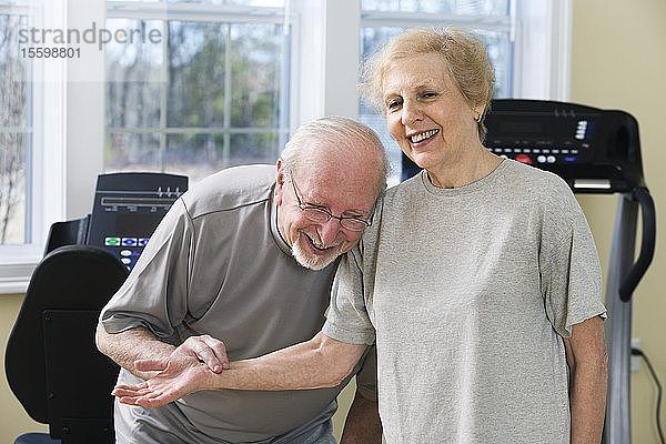 Ein älteres Paar lächelt und prüft den Puls in der Turnhalle.