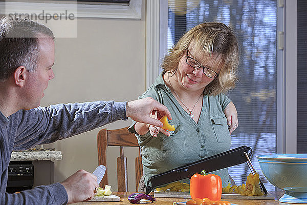 Frau mit TAR-Syndrom reibt mit ihrem Mann in der Küche Gemüse