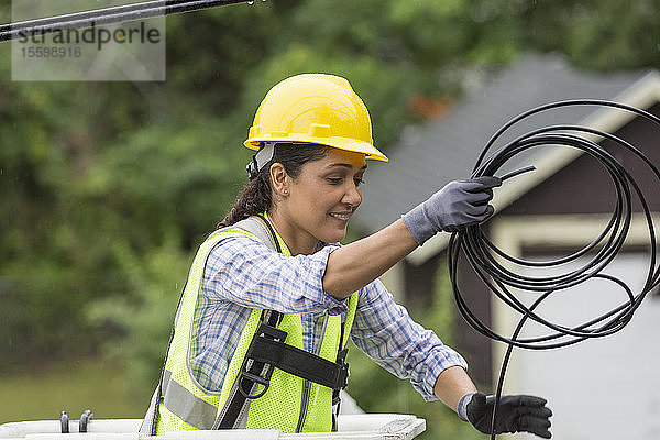 Hispanische Kabelleiterin beim Verlegen einer neuen Leitung im Regen