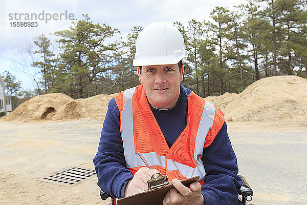 Bauingenieur mit Querschnittslähmung macht sich auf der Baustelle Notizen