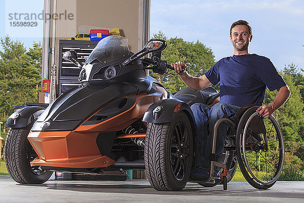 Mann mit Rückenmarksverletzung sitzt im Rollstuhl neben seinem Spezialmotorrad