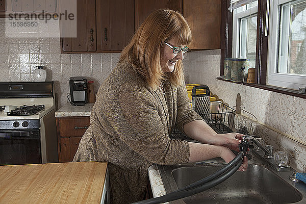 Eine blinde Frau schließt den tragbaren Geschirrspüler in ihrer Küche an