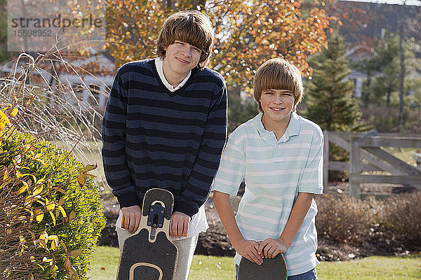 Zwei Brüder stehen mit Skateboards