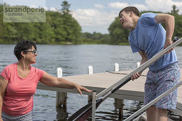 Junger Mann mit Down-Syndrom bereitet sich mit seinem Freund auf die Benutzung eines Bootes an einer Anlegestelle vor