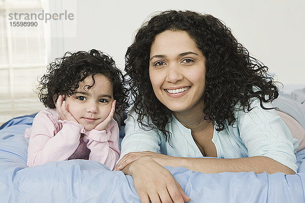 Porträt einer mittleren erwachsenen Frau mit ihrer auf dem Bett liegenden Tochter