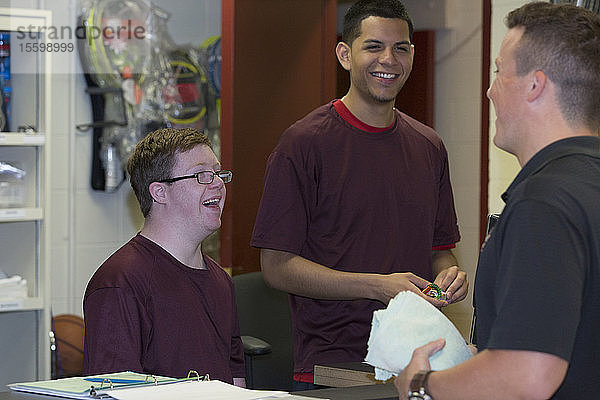 Junger Mann mit Down-Syndrom vergnügt sich mit seinen Freunden in der Ausrüstungsabteilung des College