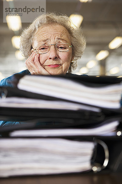 Blick auf eine ältere Frau  die mit der Arbeitsbelastung überfordert ist.