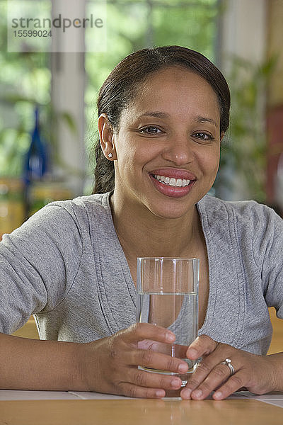 Hispanische Frau hält ein Glas Wasser