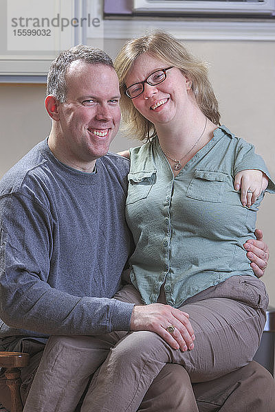 Frau mit TAR-Syndrom sitzt auf dem Schoß ihres Mannes