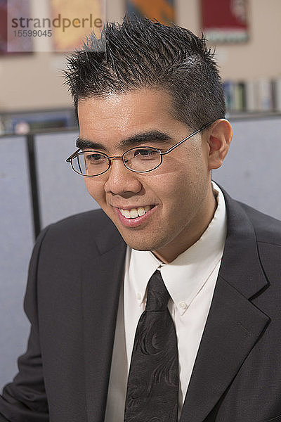 Glücklicher asiatischer Mann mit Autismus  der in einem Büro arbeitet