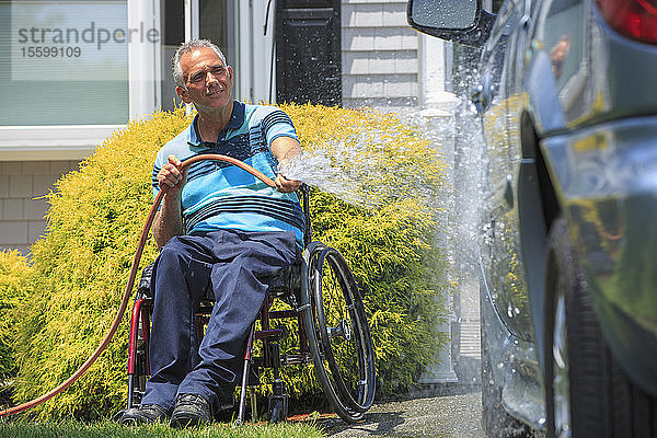 Ein Mann mit einer Rückenmarksverletzung im Rollstuhl wäscht sein zugängliches Auto