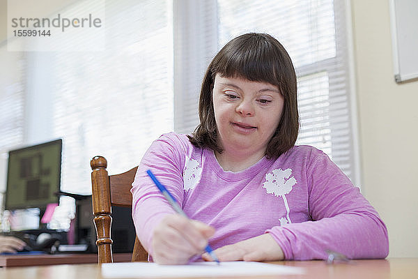 Mädchen mit Down-Syndrom schreibt auf ein Papier