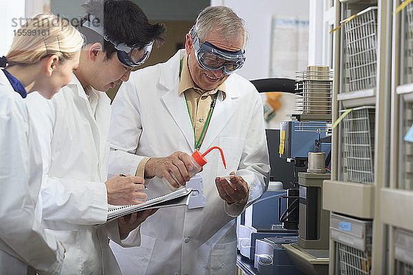 Professor bei der Arbeit mit Ingenieurstudenten  die in einem Labor Ethanol in eine Probenschale geben