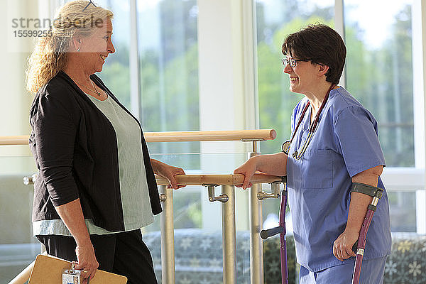 Zwei Krankenschwestern in einer Klinik  eine mit Cerebralparese an Stöcken