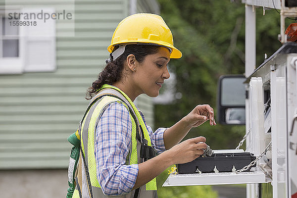 Hispanische Mitarbeiterin eines Versorgungsunternehmens mit Werkzeugen auf der Baustelle